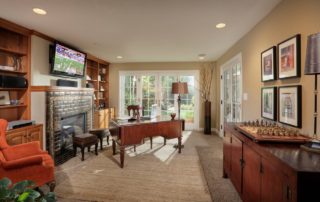 This masculine study also serves as a family room with a wall mounted flat screen television and ceiling mounted speakers. The natural light from the French doors glimmers on the surface of the built-in, stain grade Alder cabinetry and mantel. The gas fireplace is decorated with an exotic, metallic finish, tile surround.